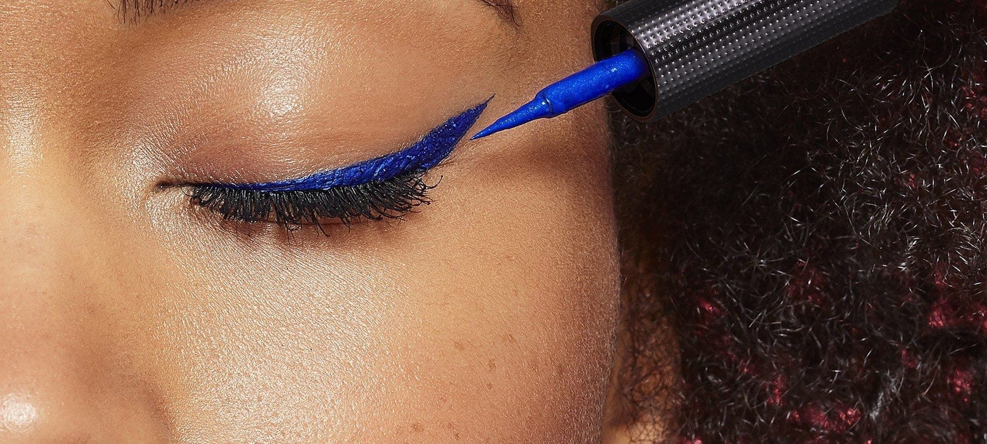 Junge Frau trägt blauen Lidstrich auf